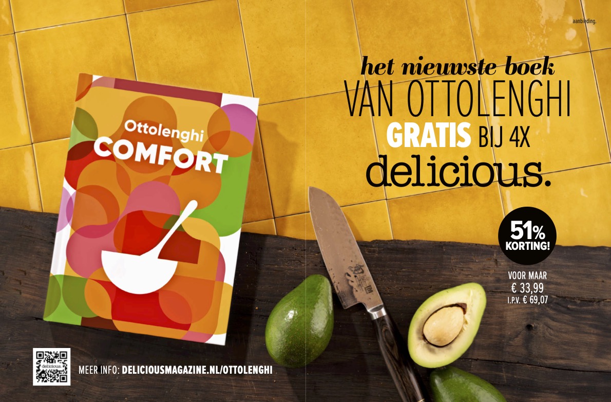 Advertentie van het boek 'Comfort' door Ottolenghi, met een kleurrijke abstracte omslag, afgebeeld op een houten oppervlak naast een mes en een avocado. Op de gele tegelachtergrond staat de tekst: 'Het nieuwste boek van Ottolenghi GRATIS bij 4x Delicious.' Daarnaast wordt 51% korting op een abonnement vermeld, met details over de prijs en een QR-code onderaan.